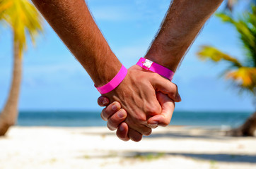 Happy gay couple on the beach holding hands