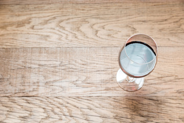 Glass with red wine on the wooden background