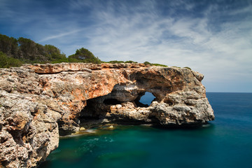 Fototapeta na wymiar Hole in the rock at Cala Sa Nau