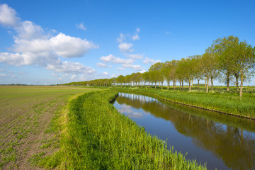 Canal along a plowed field with furrows in spring