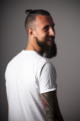 Hipster con camiseta blanca y brazo tatuado sonriendo