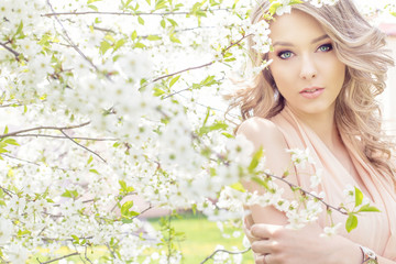 Fototapeta premium sweet girl in a light dress walking in a lush cherry orchard