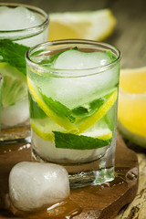 Glass of water with fresh lemon, ice and mint, selective focus