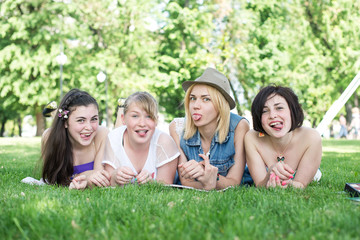 Group of happy smiling Teenage Students Outside lying on a grass