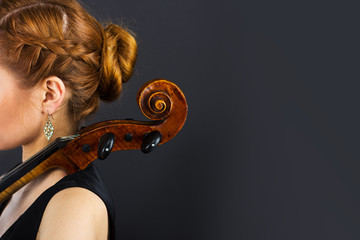 Beautiful girl with a cello on a black background. Cellist. Girl musician.
