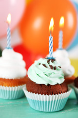Delicious birthday cupcakes on table on bright background