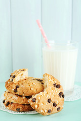 Tasty cookies and glass of milk on color wooden background