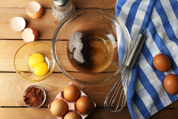 Preparation cream with eggs in glass bowl on wooden background