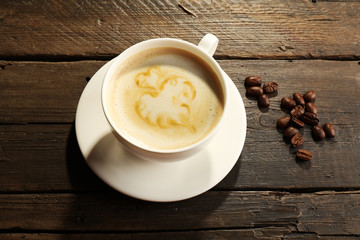 Cup of coffee latte art with grains on wooden background