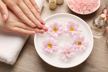 Plakat Female hands and bowl of spa water with flowers, closeup