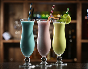 Glasses of fruit cocktails in bar on bright blurred background