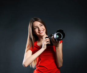 Obraz premium Young female photographer taking photos on black background