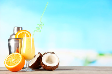 Glass of summer cocktail on wooden table on bright blurred background