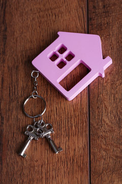 Toy house with key on wooden background