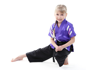 Little girl in kimono doing exercises isolated on white
