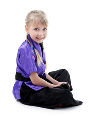 Little girl in kimono doing exercises isolated on white