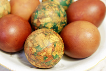 Colorful Easter eggs on white plate placed by heap