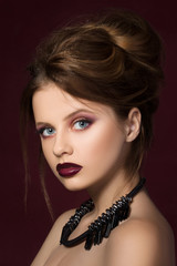 Naklejka premium Young pretty girl with vinous lipstick at dark red background
