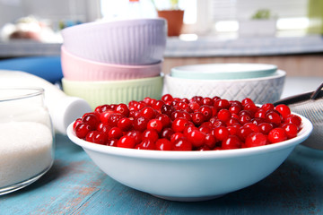 Cranberries in bowl with milk and sugar on kitchen table close up