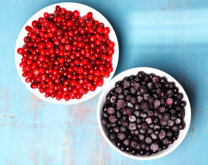 Blackberry with cranberries in bowls on wooden background