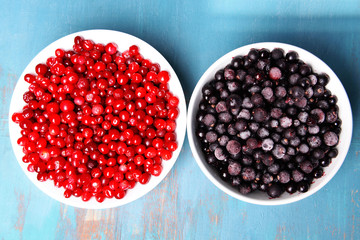 Blackberry with cranberries in bowls on wooden background