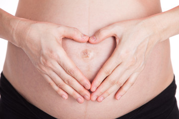 pregnant woman made her hands like heart on her abdomen