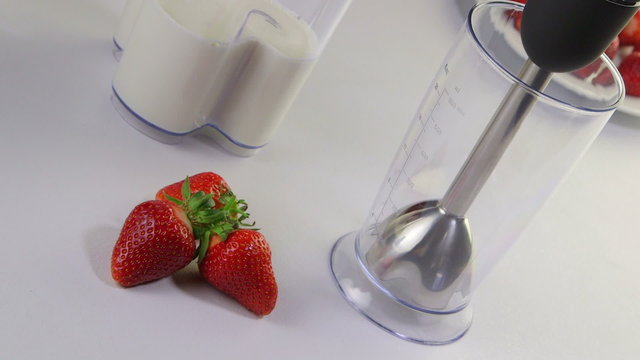 Stick hand blender making milk strawberry smoothie drink 
