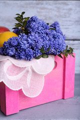 Blue bell flowers with fruits in crate on wooden background