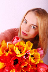 Obraz na płótnie Canvas Portrait of young woman with beautiful bouquet of tulips on wallpaper background