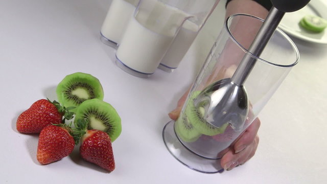  making kiwi strawberry smoothie drink using stick hand blender