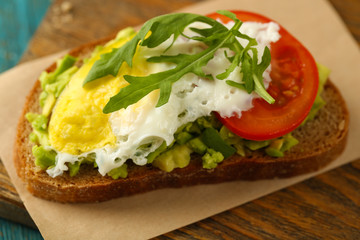 Tasty sandwich with egg, avocado and vegetables on wooden background