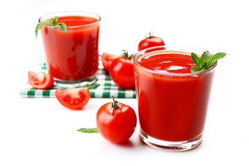Glasses of fresh tomato juice on checkered napkin, isolated on white