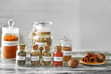 Assortment of spices in glass bottles on wooden table, on light background