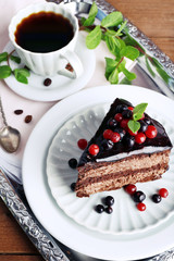 Delicious chocolate cake with berries and cup of coffee on table close up
