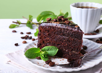 Delicious chocolate cake with mint on plate on table close up
