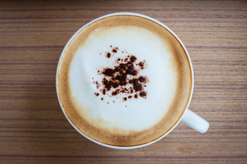 Hot coffee in a white cup placed on a wooden floor.