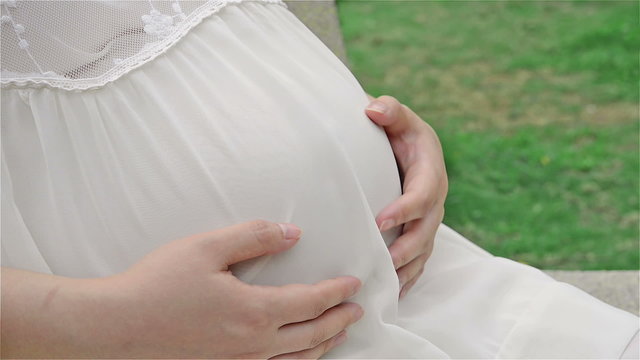 young pregnant woman petting belly feeling the baby