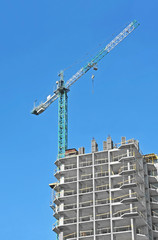 Crane and building construction site against blue sky