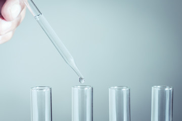 Laboratory pipette with drop of liquid over glass test tubes