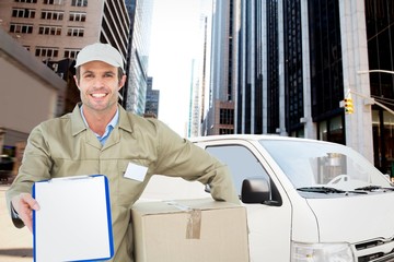 Composite image of happy delivery man with box showing clipboard