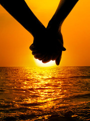 Silhouettes couples hands on sunset