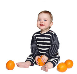 beautiful smiling baby sits with orange in hands 