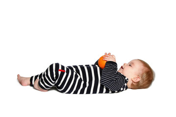 baby lying down holds and looking at orange on white background