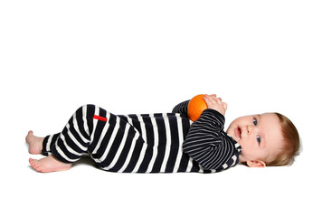 baby lying down and holds orange on white background