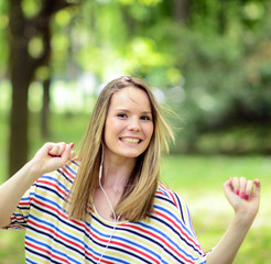 Female student girl outside in park listening to music on headph