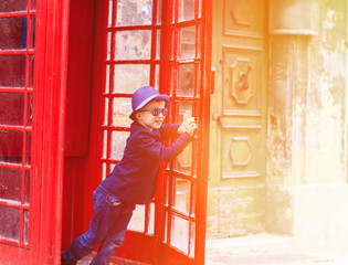 little boy with red telephone box in the city