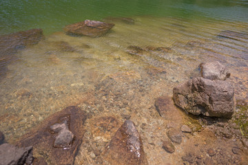 Fototapeta na wymiar Klares Wasser im Bergsee mit Steinen