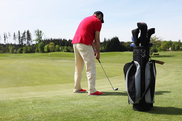Mann mit rotem Polo am Putter