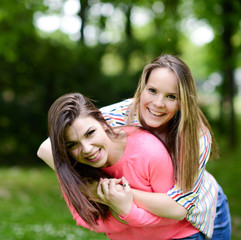 Two young girl friends in a hug at park