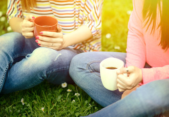 Young women drinking coffee at park and enjoying summer day